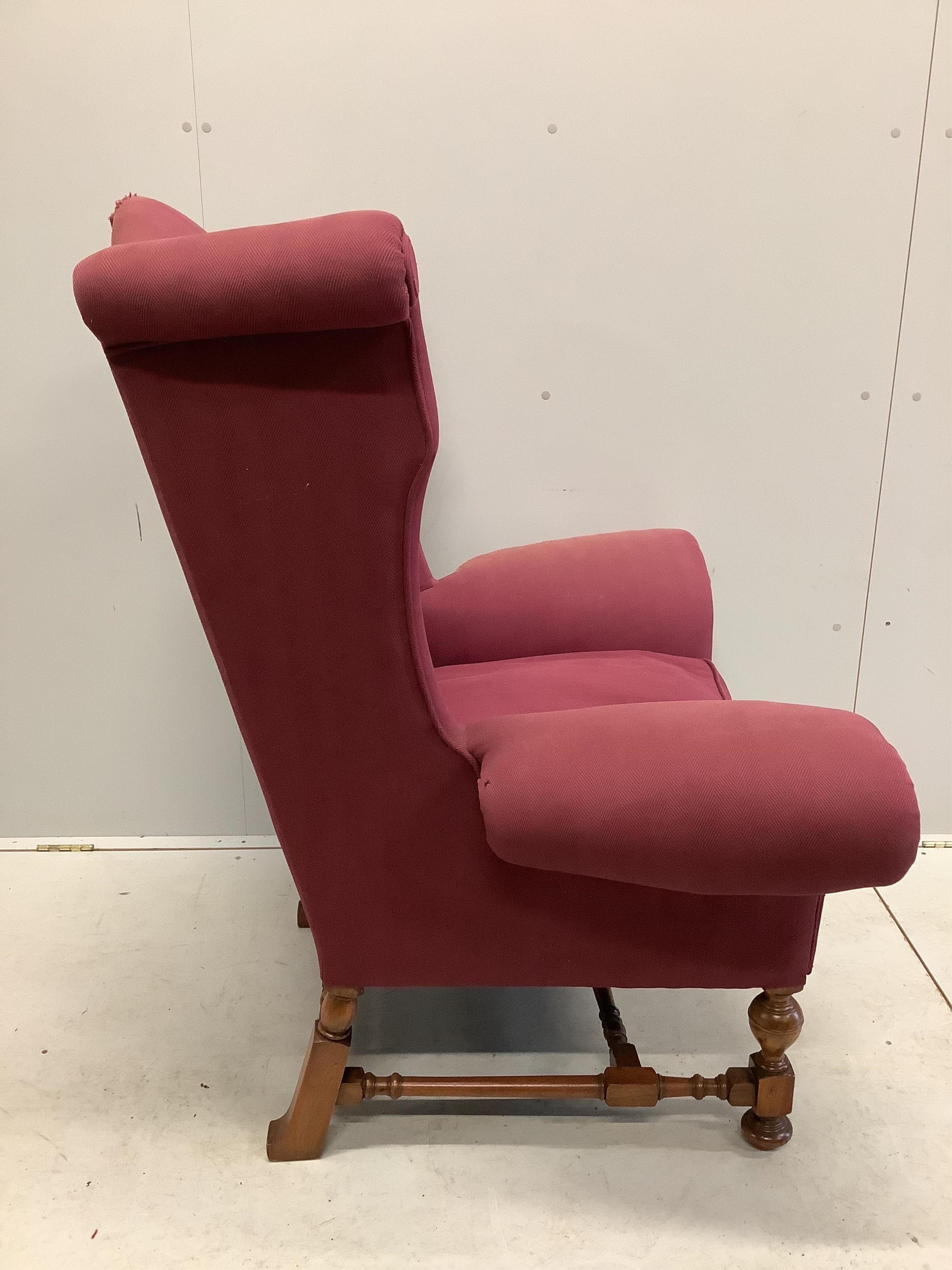 A Queen Anne revival wing armchair with wide scroll arms on turned walnut underframe, width 106cm, depth 70cm, height 120cm. Condition - fair, upholstery poor